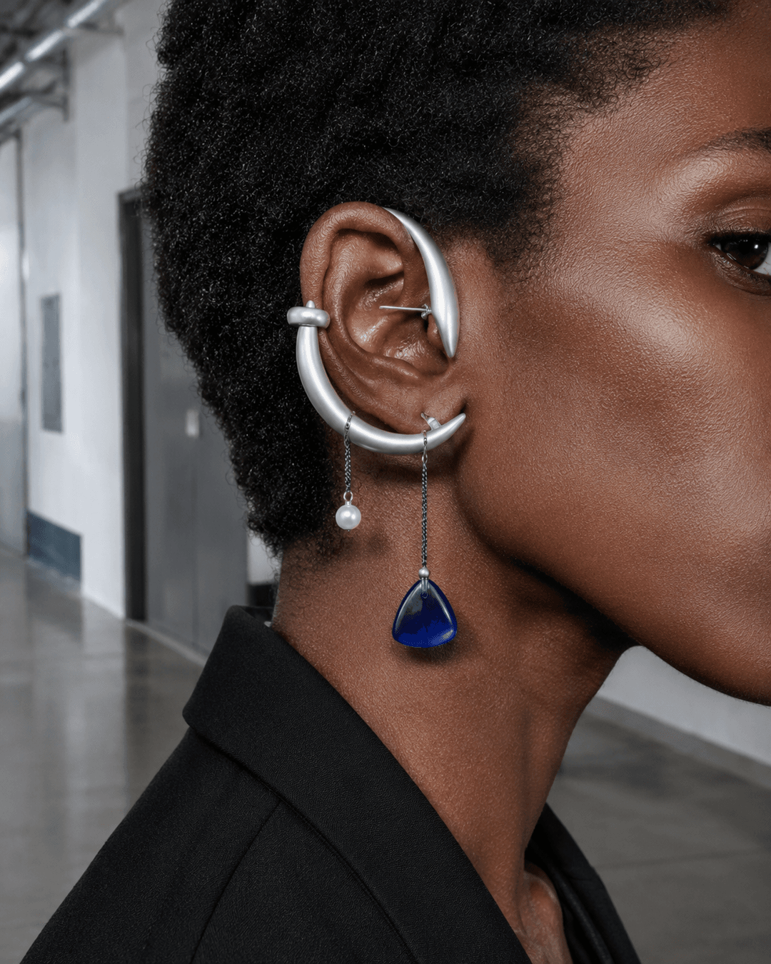 Editorial ear close-up of an adult model wearing a cobalt resin, titanium arc and pearl convertible ear construction