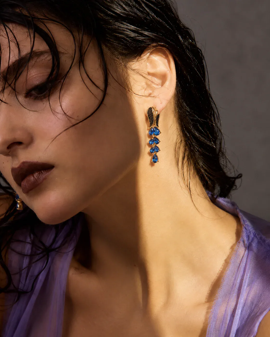 Adult model wearing sculptural drop earrings in an editorial close crop with the jewelry construction clearly visible