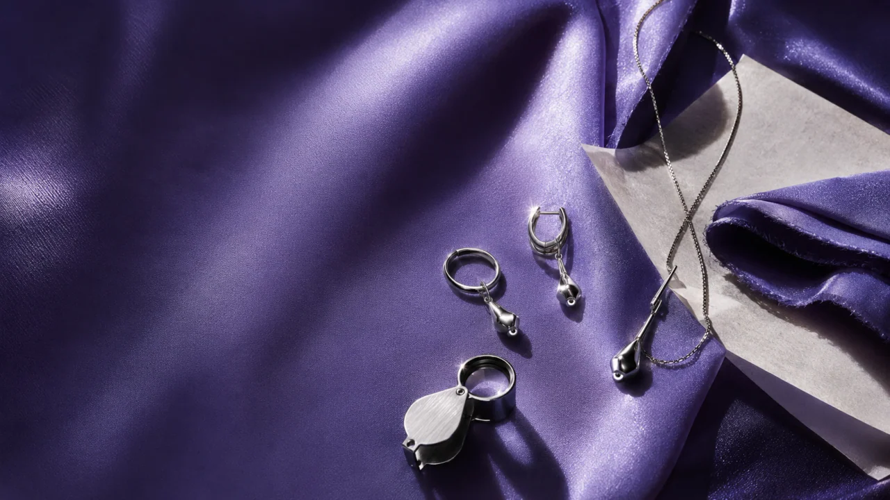 Hands examining a small jewelry connection in a bright material study