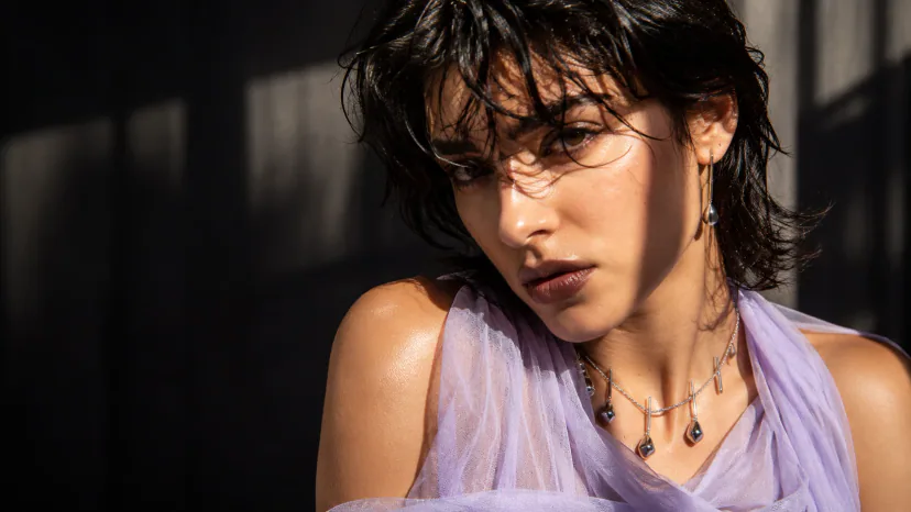 Adult model wearing a sculptural silver drop necklace and long earring in a young editorial portrait