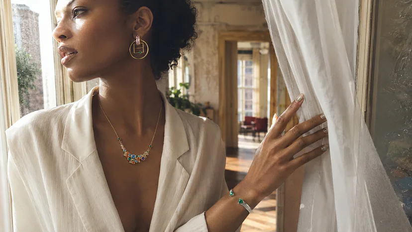 Black fashion model in a sunlit New York apartment wearing Switchroom gemstone jewelry and an editorial manicure
