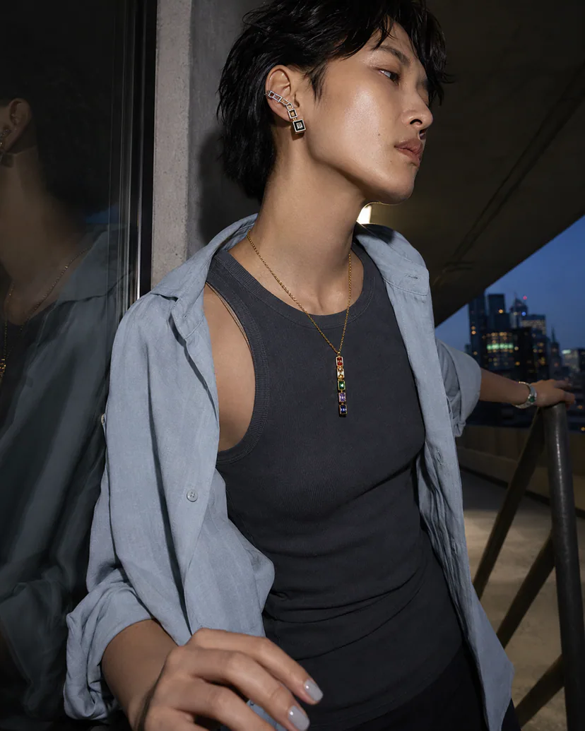 Adult traveler wearing sculptural earrings and a necklace in a rooftop evening setting