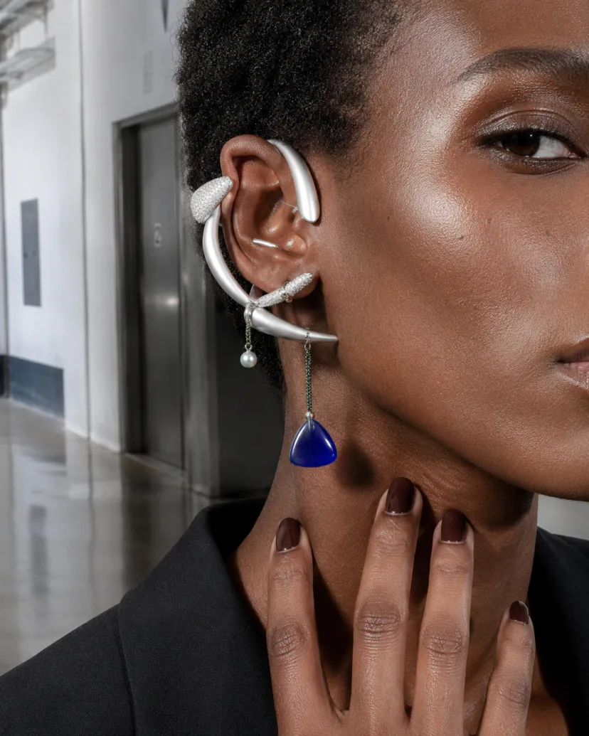 Editorial ear close-up of an adult model wearing cobalt resin, titanium arcs and a pearl counterweight