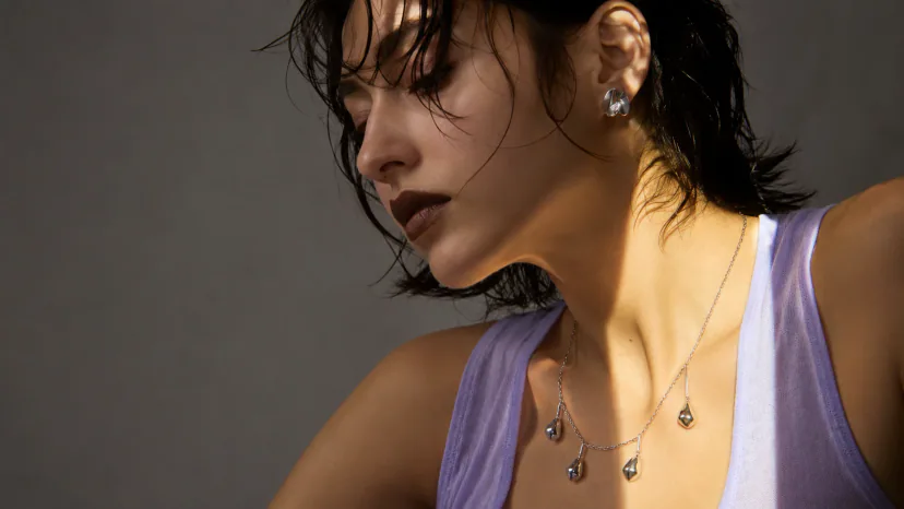 Adult model wearing a sculptural silver necklace and earrings in a jewelry-led editorial portrait