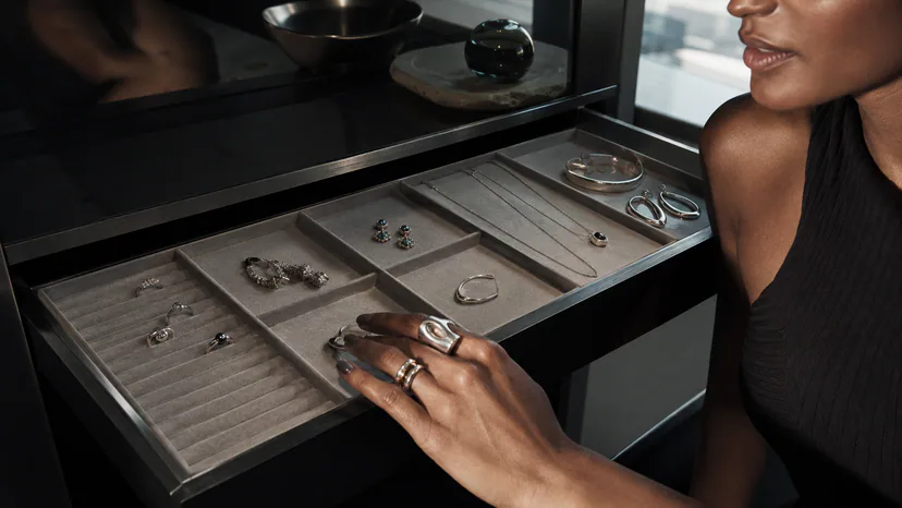 Adult wearer selecting sculptural jewelry from a visible compartment organizer