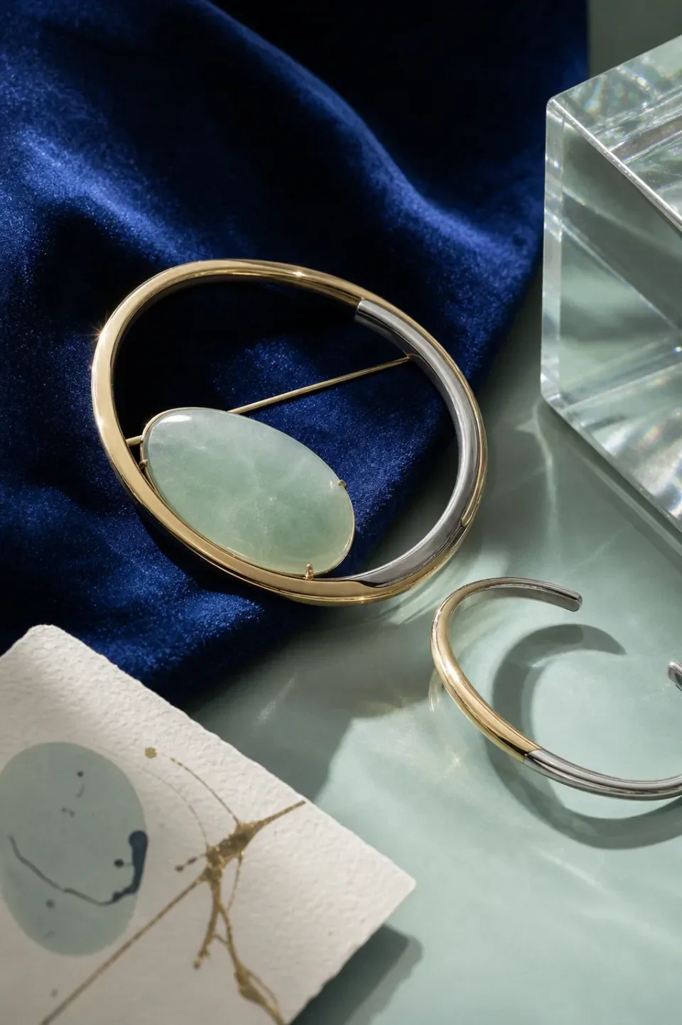 Mixed-metal collector hero object with a companion cuff and art matter on cobalt and celadon