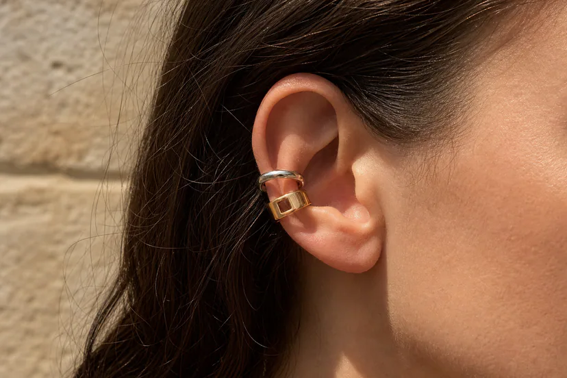 Close ear styling view of silver and gold sculptural jewelry with contrasting metal finishes