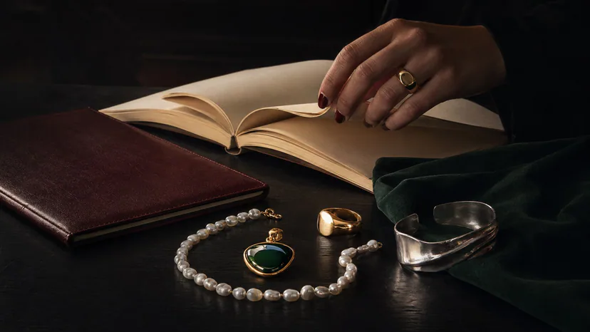 dark academia jewelry with transparent gray nails on a greige library table