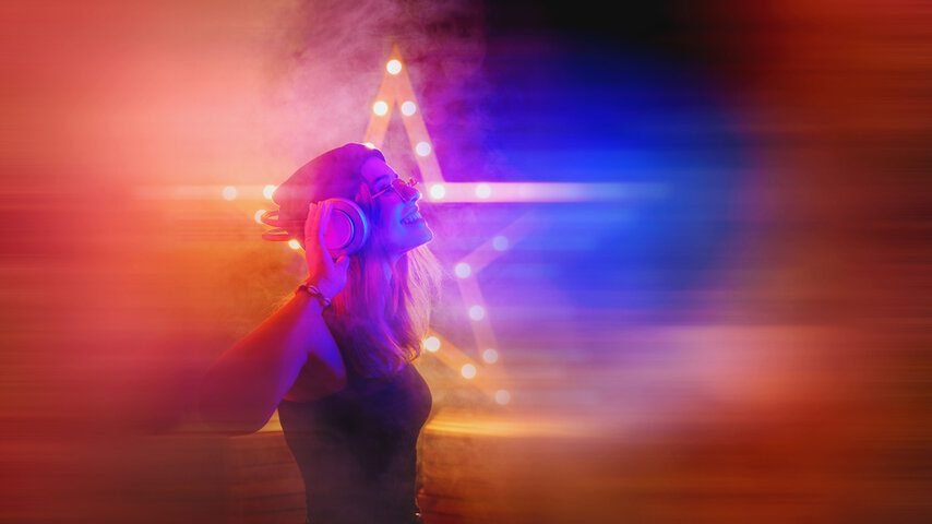 Young woman enjoying music in neon lights, stepping into a more playful and expressive identity.