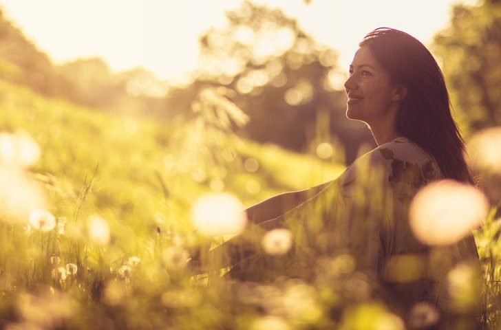 Woman sitting in a sunlit meadow, reflecting on new possibilities for her life.